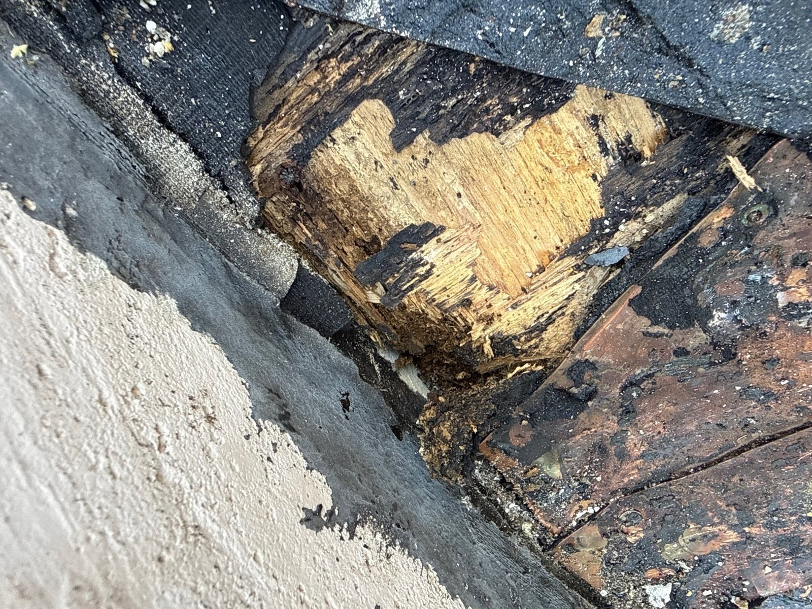 Rotten roof decking exposed beneath an intact-looking tile roof return