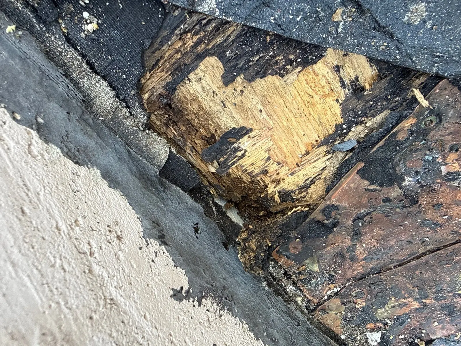 Rotten roof decking exposed beneath an intact-looking tile roof return